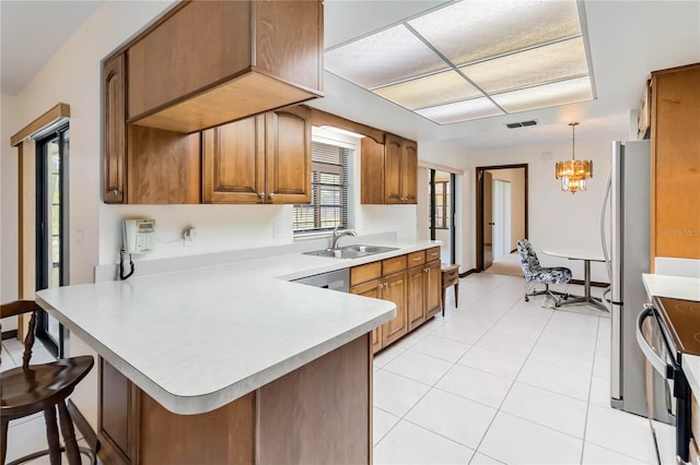 kitchen featuring a breakfast bar area, a sink, light countertops, a peninsula, and stainless steel appliances