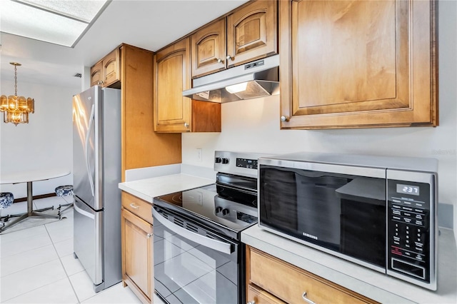 kitchen with an inviting chandelier, brown cabinetry, light countertops, under cabinet range hood, and appliances with stainless steel finishes