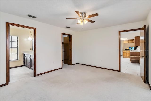 unfurnished bedroom featuring baseboards, visible vents, light carpet, and ensuite bath