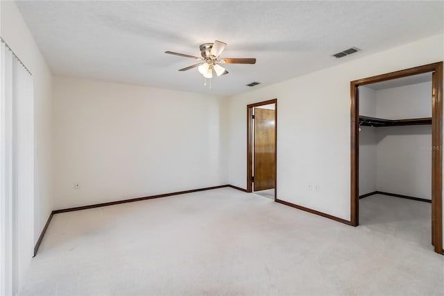 unfurnished bedroom with a walk in closet, baseboards, light carpet, and visible vents