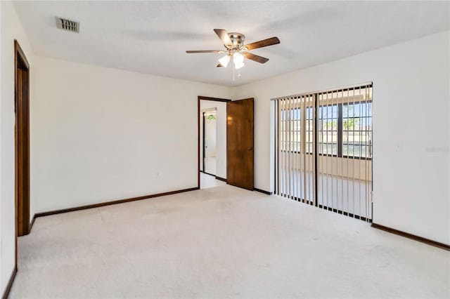 empty room with carpet floors, baseboards, a ceiling fan, and visible vents