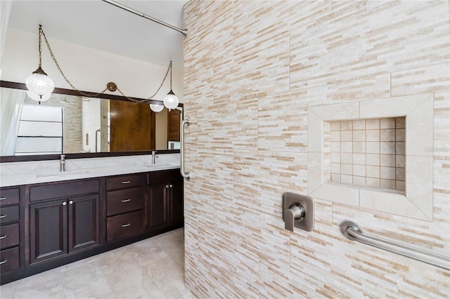 bathroom with double vanity, a sink, and tiled shower