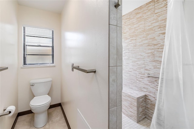 bathroom with tile patterned floors, baseboards, a tile shower, and toilet