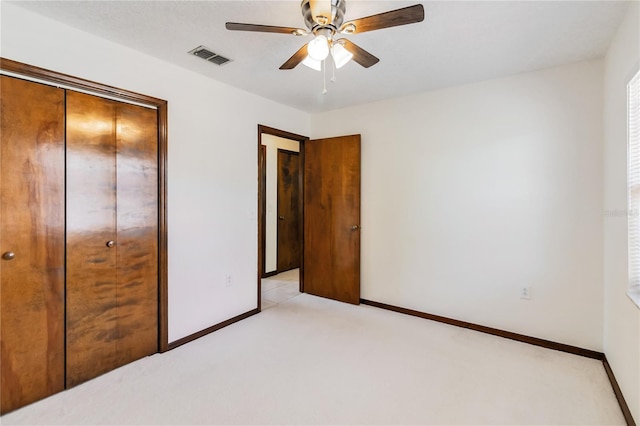 unfurnished bedroom featuring visible vents, a closet, baseboards, ceiling fan, and light colored carpet