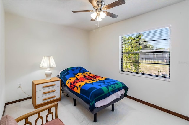 bedroom with baseboards, ceiling fan, and light carpet