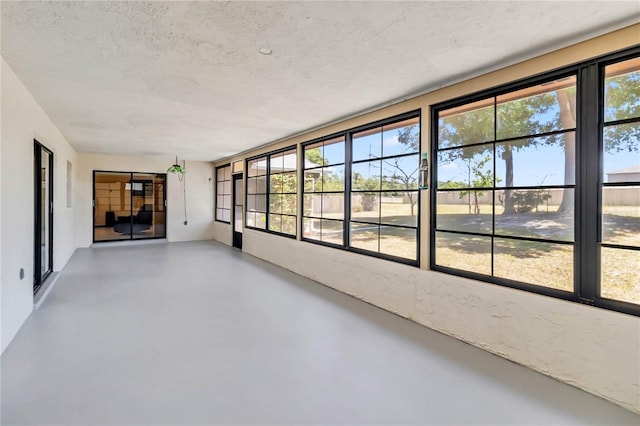 unfurnished sunroom with concrete flooring and a textured ceiling