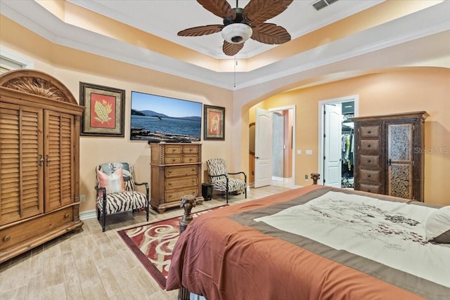 11502 Waterstone Loop Dr, Windermere, FL 34786 - bedroom with arched walkways, baseboards, light wood finished floors, a tray ceiling, and ceiling fan
