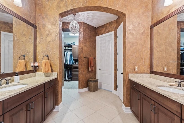 11502 Waterstone Loop Dr, Windermere, FL 34786 - bathroom featuring two vanities, tile patterned flooring, a walk in closet, and baseboards