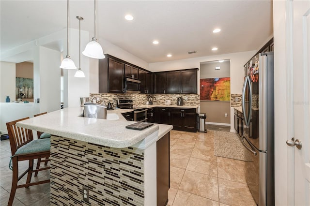 2952 Boating Blvd, Kissimmee, FL 34746 - kitchen with decorative backsplash, a peninsula, dark brown cabinets, a kitchen breakfast bar, and appliances with stainless steel finishes