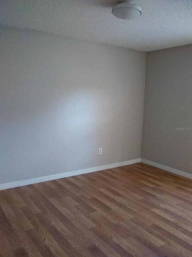 2011 N 61st St, Tampa, FL 33619 - unfurnished room with wood finished floors, a textured ceiling, and baseboards