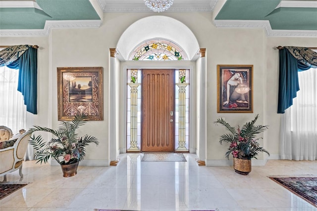 foyer entrance featuring crown molding, baseboards, and a chandelier