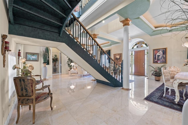 entryway with stairs, ornamental molding, marble finish floor, a high ceiling, and ornate columns