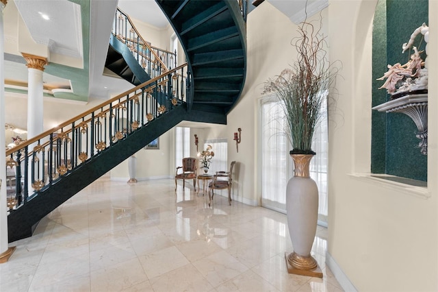 staircase with crown molding, baseboards, marble finish floor, a high ceiling, and a wealth of natural light