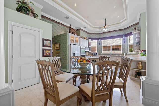dining space featuring visible vents, ornamental molding, wallpapered walls, a tray ceiling, and a ceiling fan
