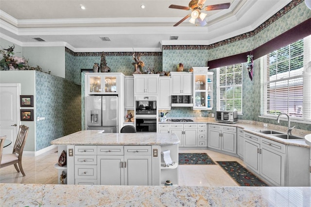 kitchen with ornamental molding, a sink, wallpapered walls, a ceiling fan, and appliances with stainless steel finishes
