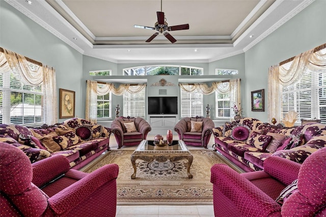 living area featuring a raised ceiling, plenty of natural light, ornamental molding, and a ceiling fan