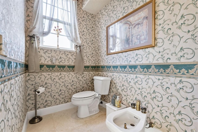 half bath with a bidet, toilet, and wallpapered walls