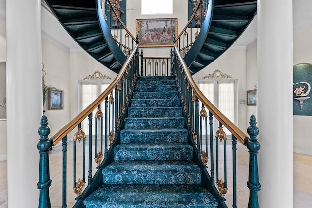 stairs featuring plenty of natural light, baseboards, a high ceiling, and crown molding