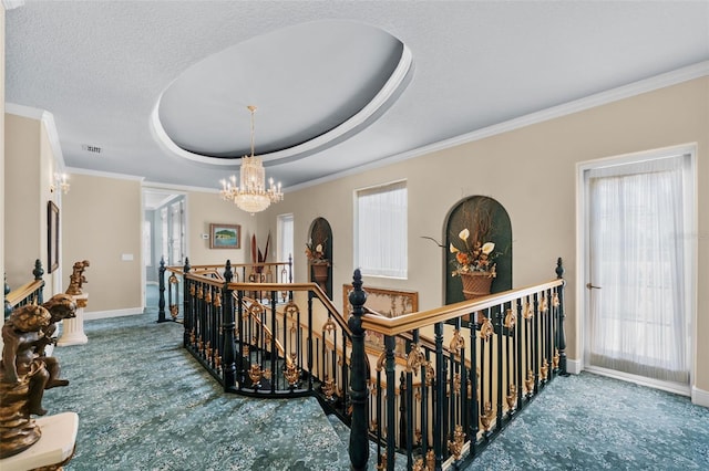 corridor with crown molding, baseboards, a raised ceiling, a notable chandelier, and an upstairs landing