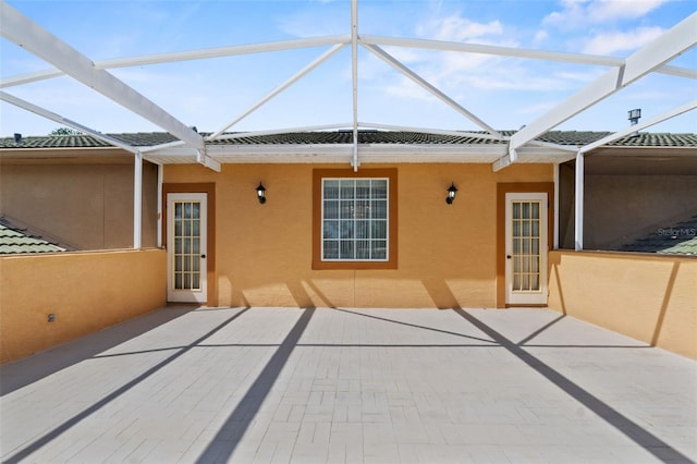 back of house featuring a patio, glass enclosure, and stucco siding