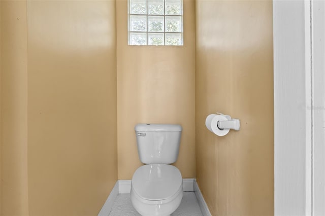bathroom with baseboards, tile patterned floors, and toilet