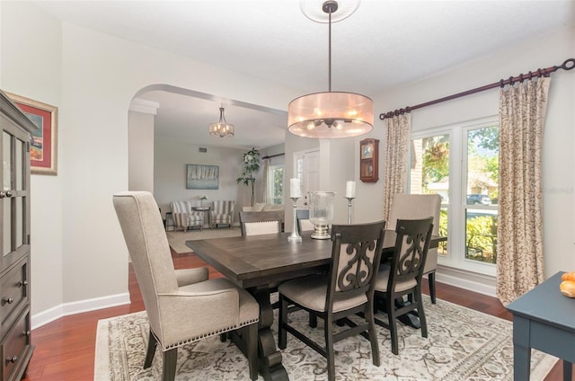 dining area with dark wood-style flooring, baseboards, a notable chandelier, and arched walkways