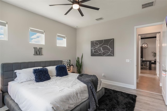 bedroom featuring baseboards, a ceiling fan, light wood-type flooring, and visible vents