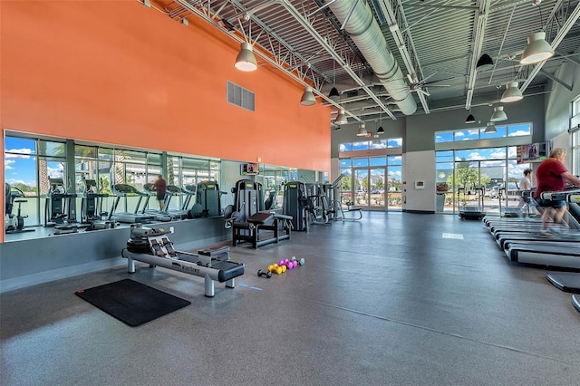 exercise room featuring visible vents and a towering ceiling