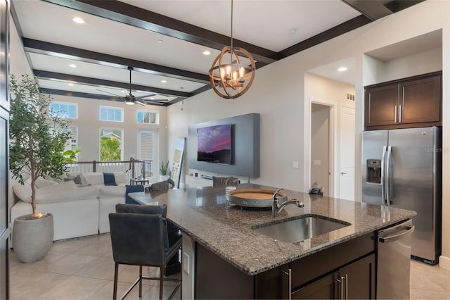 kitchen with stainless steel appliances, open floor plan, dark brown cabinetry, and a sink