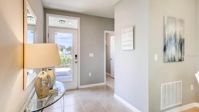 doorway featuring light tile patterned floors, visible vents, and baseboards