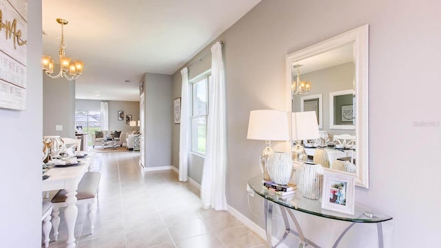 corridor with tile patterned flooring, a notable chandelier, and baseboards