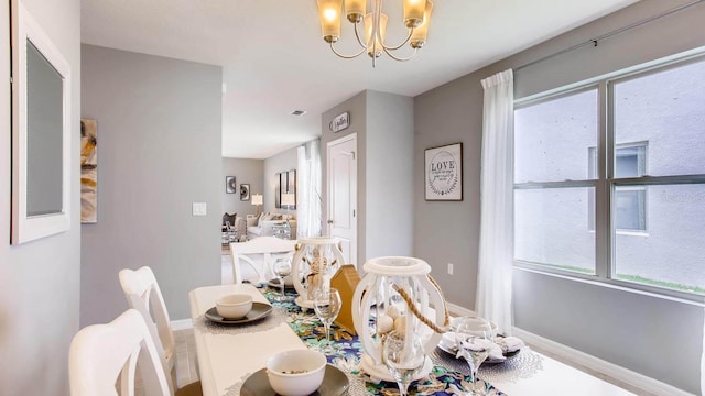 dining area with a chandelier, baseboards, and plenty of natural light