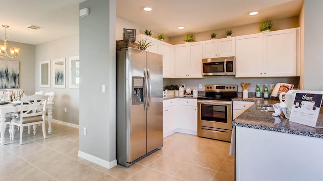 kitchen with light tile patterned floors, white cabinetry, stainless steel appliances, and a notable chandelier