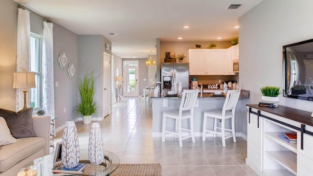living area with baseboards, visible vents, light tile patterned flooring, and recessed lighting