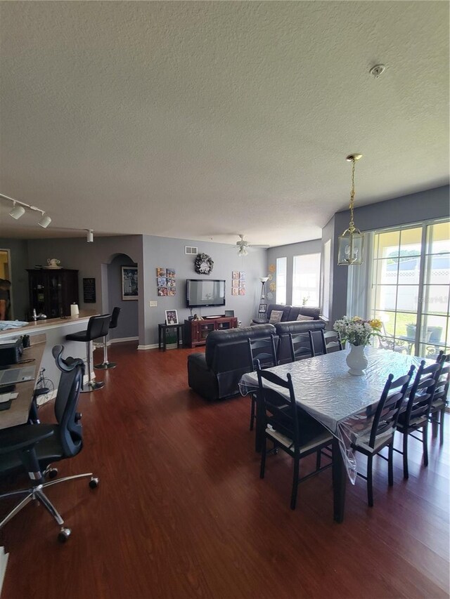 dining space featuring a textured ceiling, visible vents, arched walkways, wood finished floors, and baseboards