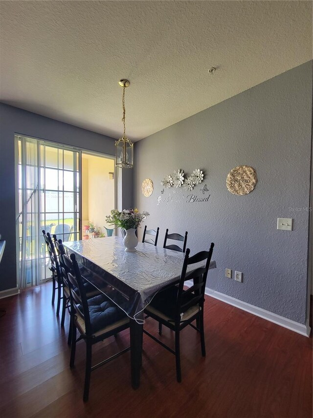 dining room featuring baseboards, a textured ceiling, dark wood finished floors, and a textured wall
