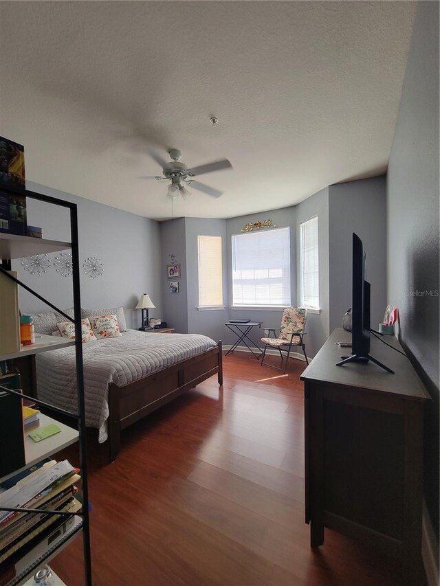 bedroom featuring a ceiling fan, a textured ceiling, and wood finished floors