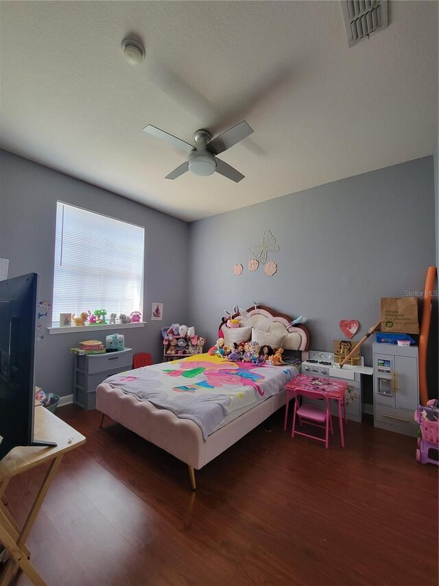 bedroom featuring a ceiling fan, wood finished floors, and visible vents