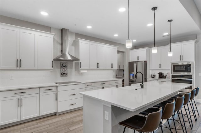 3332 Lone Cypress Pt, Oviedo, FL 32765 - kitchen with wall chimney range hood, appliances with stainless steel finishes, a breakfast bar area, a kitchen island with sink, and a sink