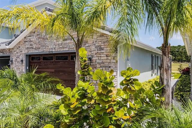3078 Isles Way, New Smyrna Beach, FL 32168 - view of side of home with stone siding, an attached garage, and stucco siding