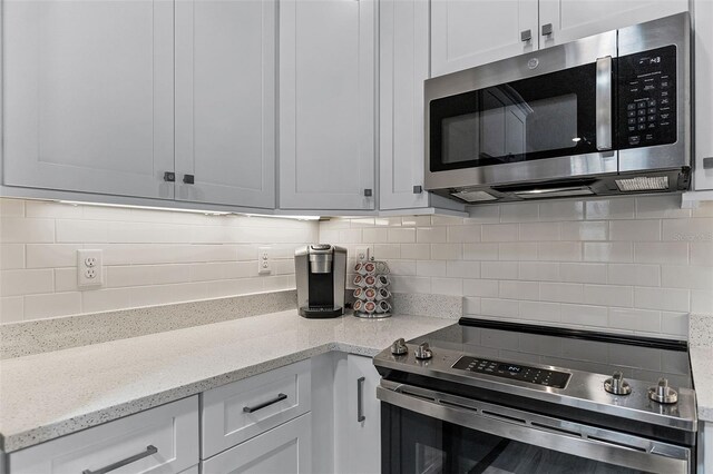 3078 Isles Way, New Smyrna Beach, FL 32168 - kitchen with stainless steel appliances, decorative backsplash, light stone countertops, and white cabinets