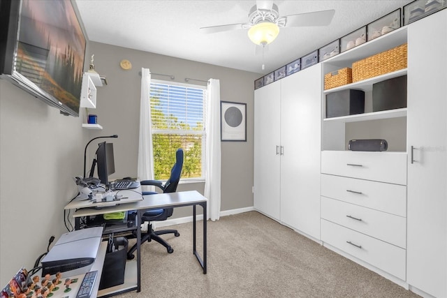 office space with baseboards, light carpet, and a ceiling fan