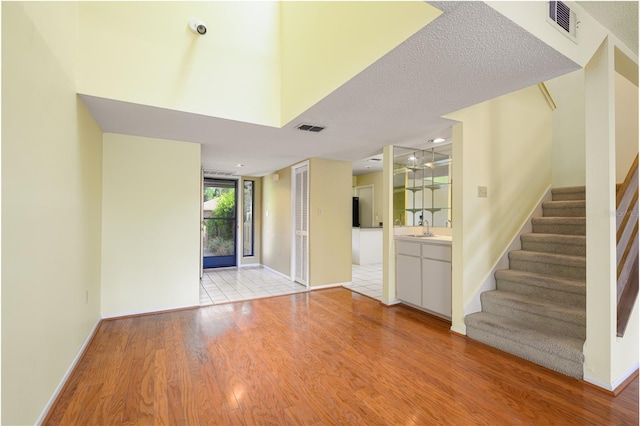 unfurnished living room with wood finished floors, visible vents, baseboards, and stairs