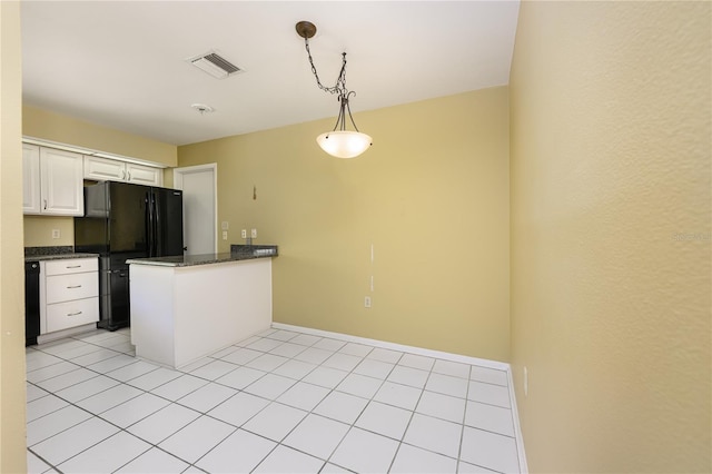 kitchen featuring visible vents, a peninsula, white cabinetry, hanging light fixtures, and freestanding refrigerator