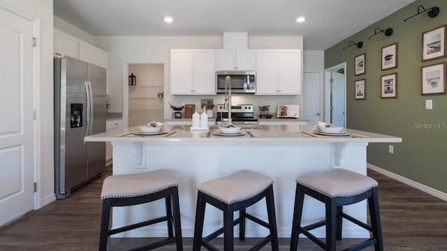 8375 Madrid St, Lakeland, FL 33810 - kitchen with dark wood-style floors, stainless steel appliances, a breakfast bar area, white cabinetry, and light countertops