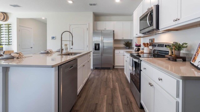 8375 Madrid St, Lakeland, FL 33810 - kitchen with white cabinets, a sink, visible vents, stainless steel appliances, and dark wood-style floors