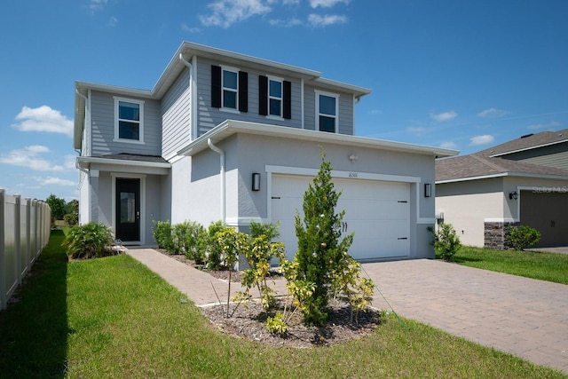 traditional home featuring fence, an attached garage, stucco siding, a front yard, and driveway