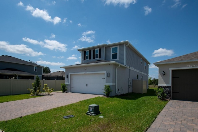 view of property exterior featuring an attached garage, fence, decorative driveway, stucco siding, and a lawn