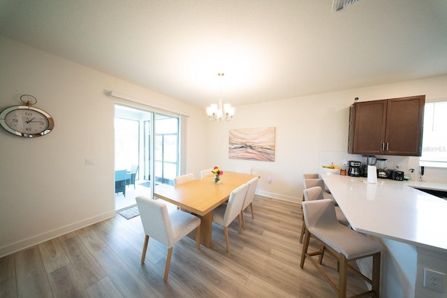 dining space featuring baseboards, light wood finished floors, and a notable chandelier