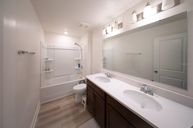 bathroom featuring double vanity, toilet, a sink, and wood finished floors